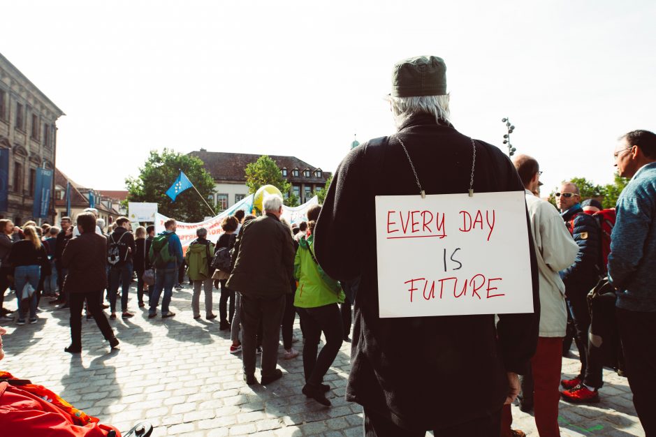 ambition - a photo of a man with his back to the camera, a sign reading 'every day is future' on his back