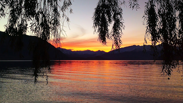 Happiness - sunset over mountains with a lake in the forefront of the image.