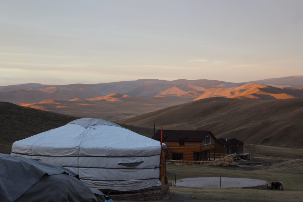 Mongolia - a ger in the foreground, with hills touched by sunlight in the background.