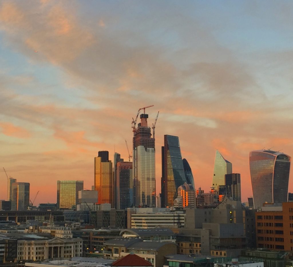 Sunset over the City of London. An orange sky and the skyline includes the Walkie Talkie building, the Cheesegrater and other high rise blocks that have been built.