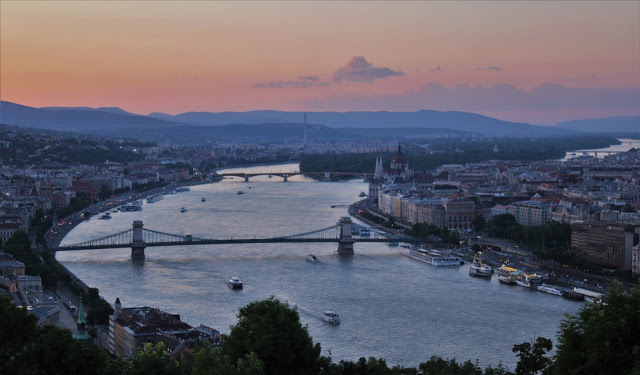 travel without travelling - sunset across Budapest, the river spanned by a bridge.