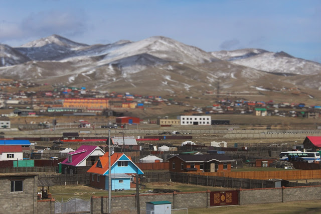 Mongolia - snow capped hills in the background with colourful houses in the foreground.