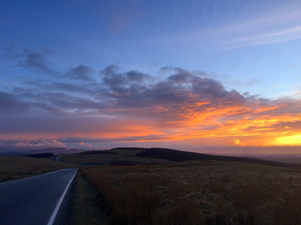 2019 - a sunset over the Welsh hills. Golden red skies and a road in the bottom left of the image.