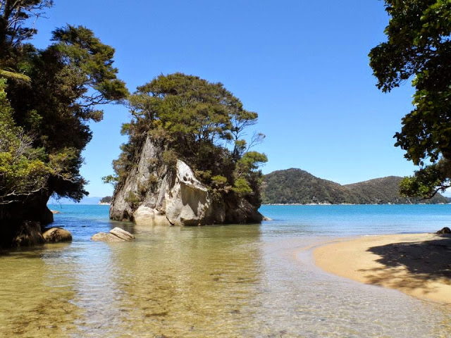 Abel Tasman National Park. Turquoise blue shallow water with a rocky outcrop in the background.