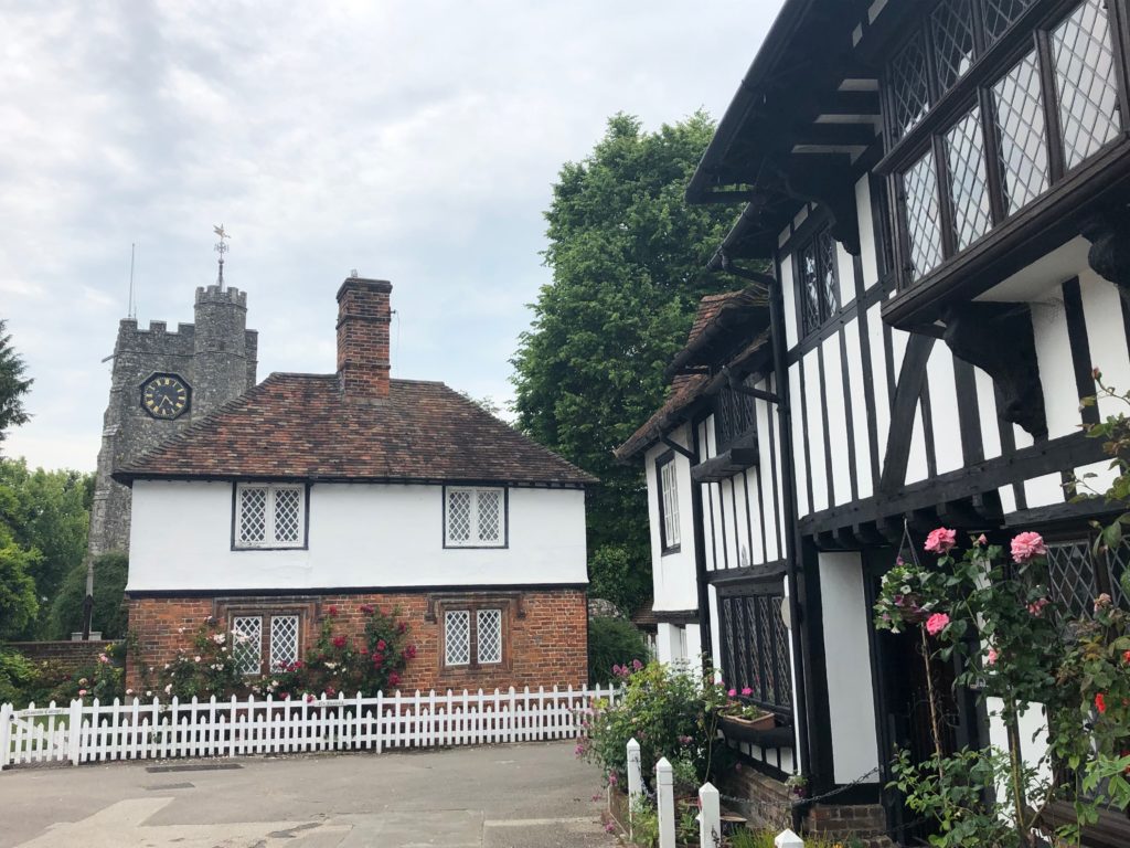 Tudor timber framed houses and a church on a village square.