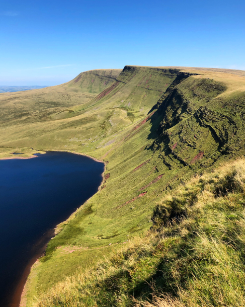 August 2019 - a view of a lake from the top of a mountain, with bright blue skies overhead.