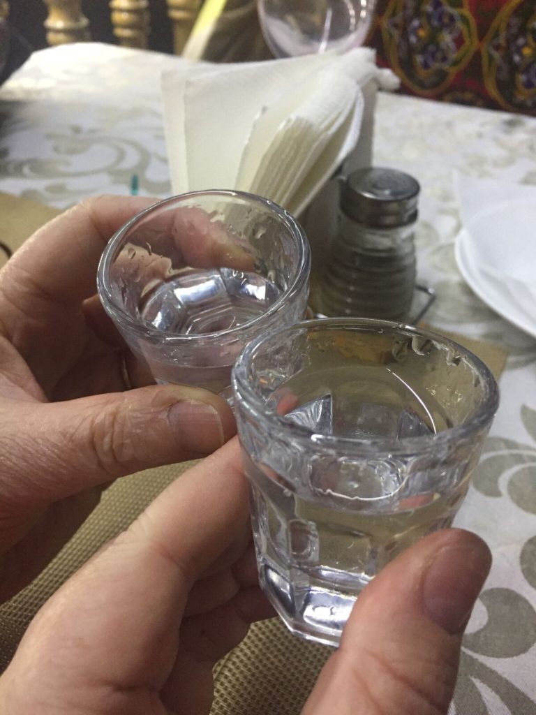 Two shot glasses filled with vodka, cheers-ing together.