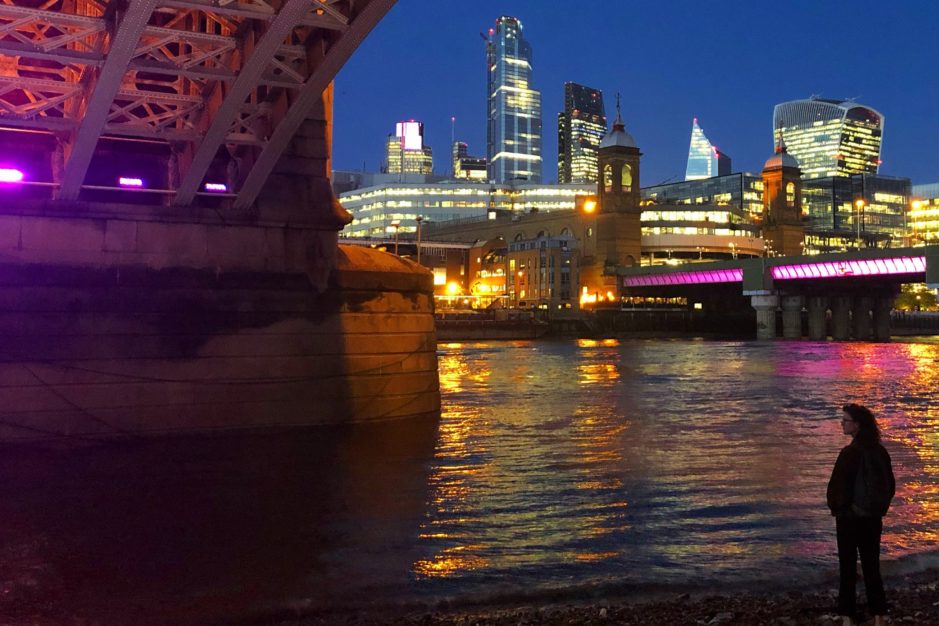 October 2019 - underside of Southwark Bridge in the dark with the city of London behind lit up.