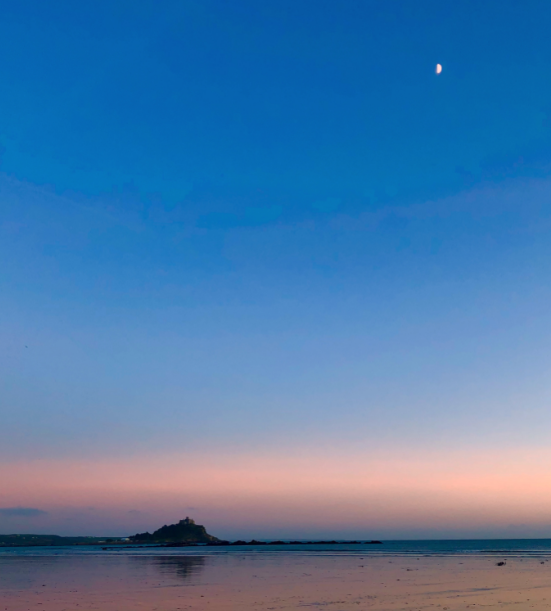 2020 - St Michael's Mount jutting up from the sand. It is silhouetted against a pink and blue sky and the moon is in the top right corner of the image. 