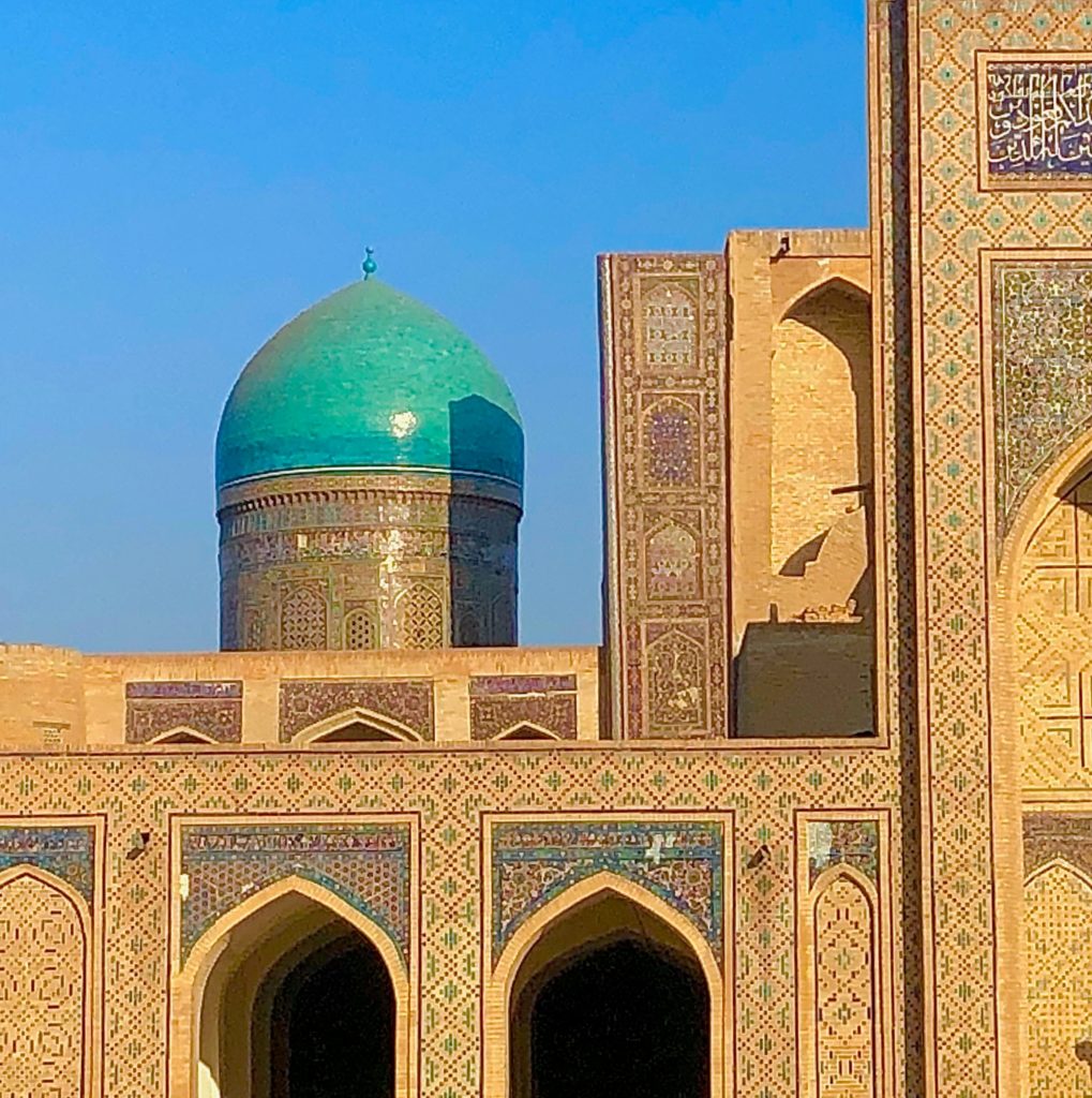 Budget Uzbekistan - A close up shot of a turquoise dome shining in the sunlight, with patterned facades in the foreground.