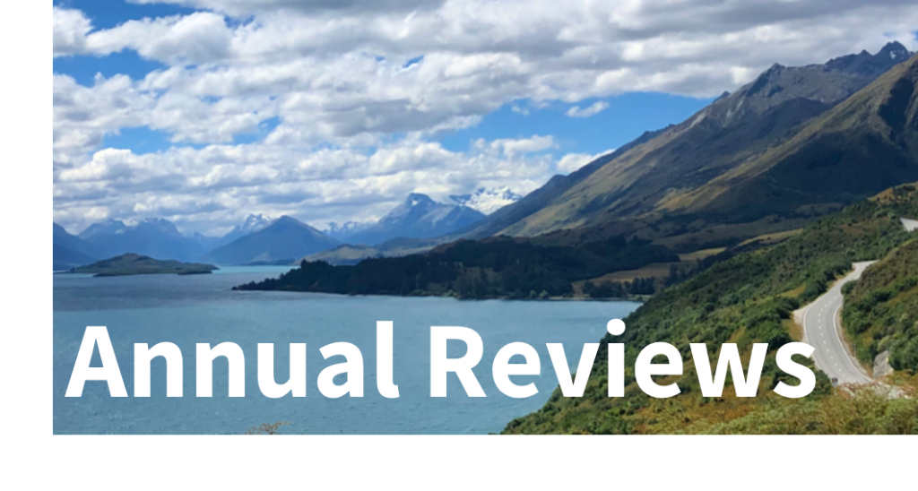 Blog Reviews: Annual - text overlaying an image of a lake to the left, with a road snaking into the hills on the right and a cloudy sky above.