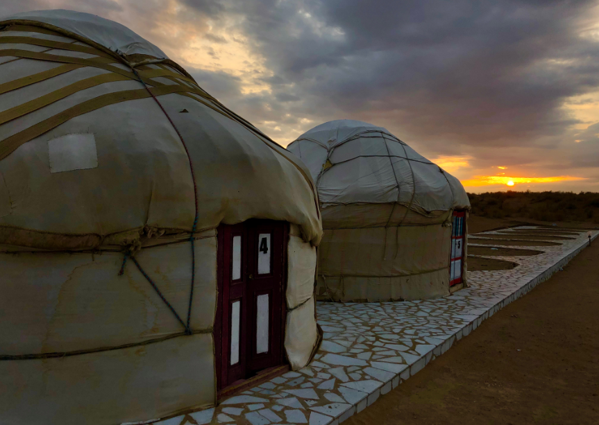 Yurts at sunset - two yurts side by side with a sunset in the background under a cloudy sky.