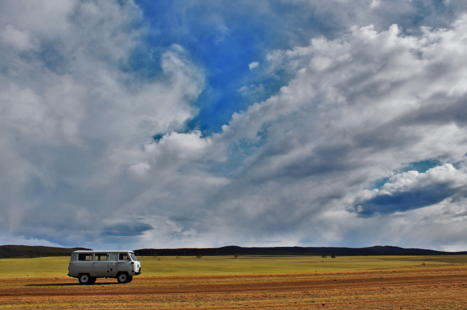 Transport on Olkhon Island - a Russian jeep, set against a backdrop of big cloud filled skies and orange-green grassland.