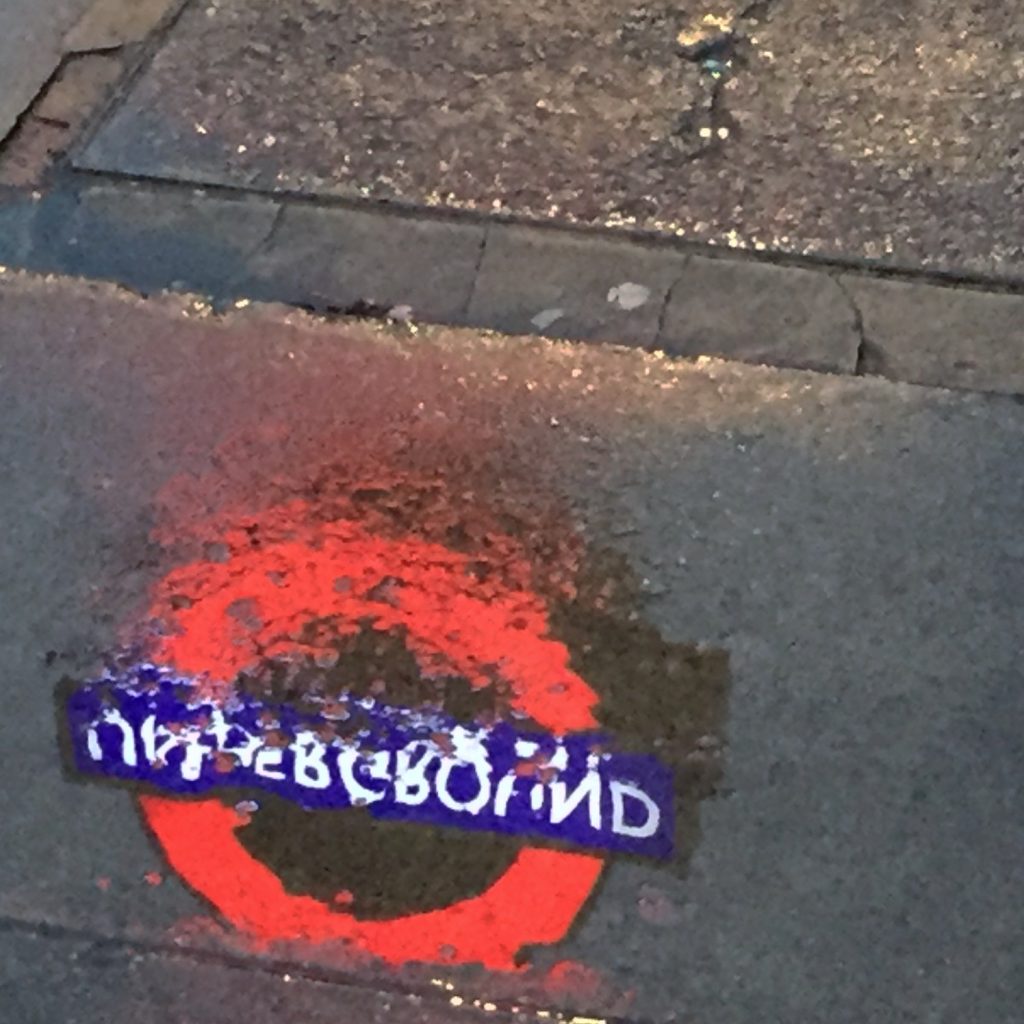 Happiness - the reflection of an Underground roundel on a wet pavement.