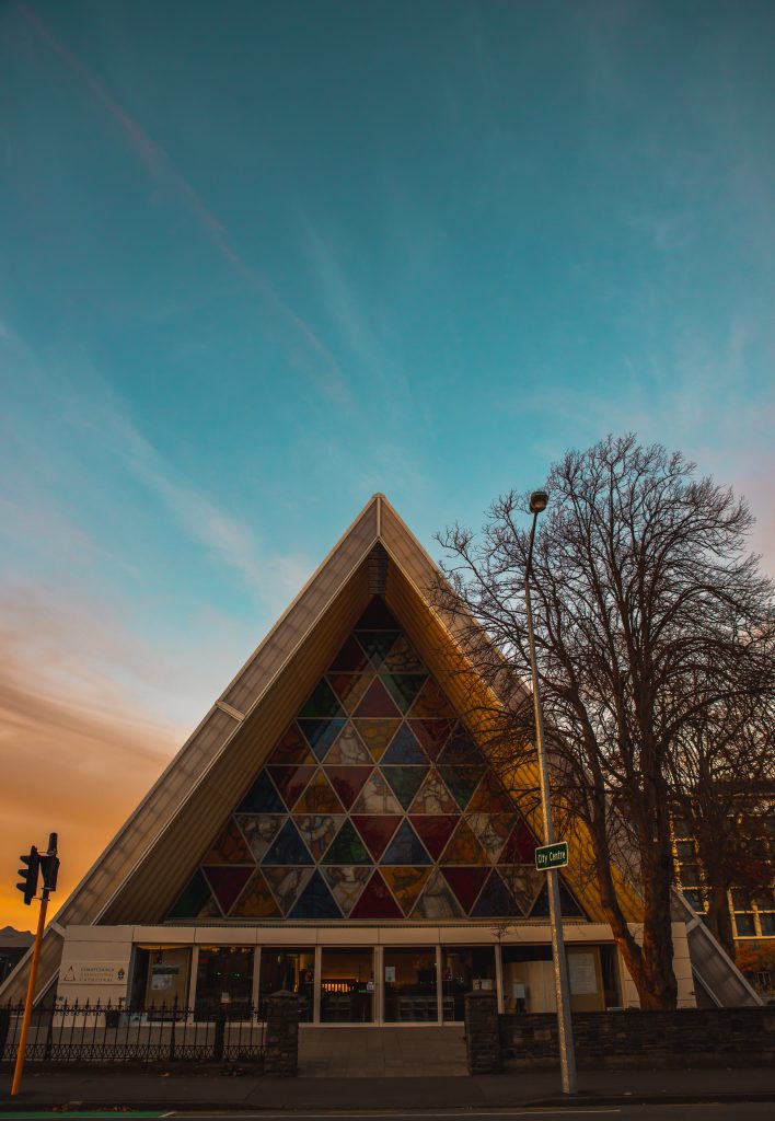 An image of Christchurch's Transitional Cathedral. A triangular structure, with triangle 'stained glass' windows.
