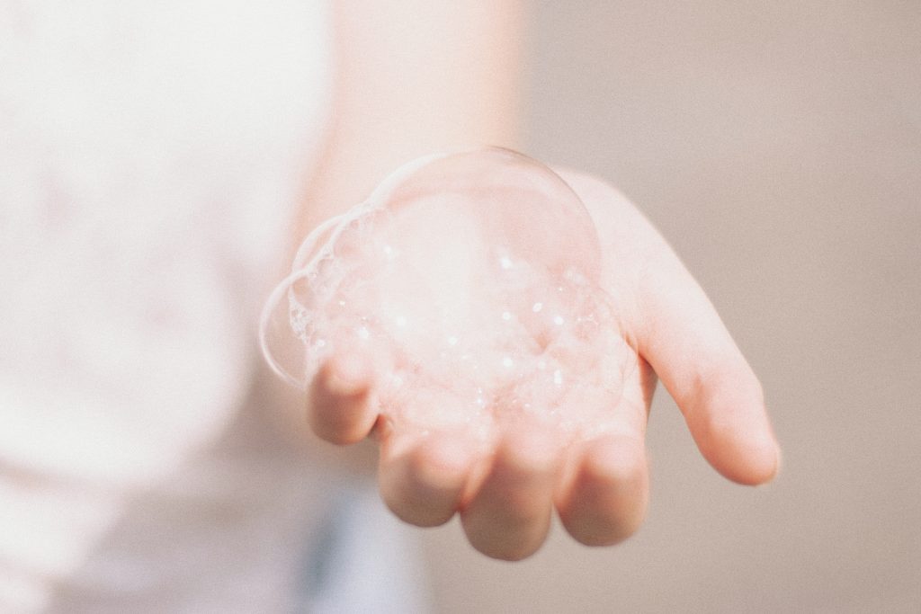 Lockdown - a hand reaching out with soap bubbles in the palm.