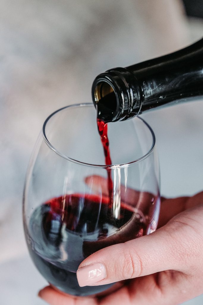 Close up image of red wine being poured into a glass.