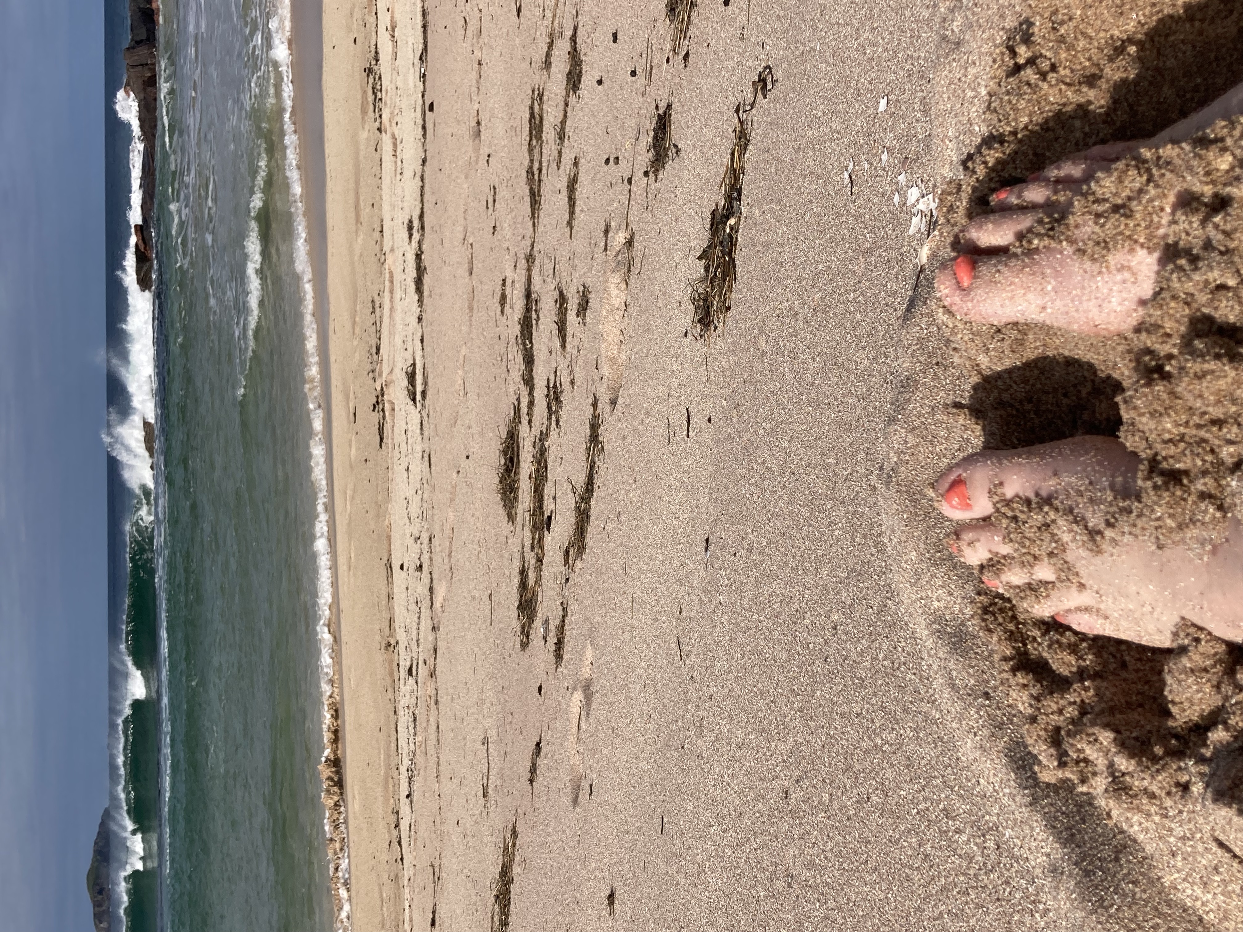 A view of my feet in the sand with the waves in the background